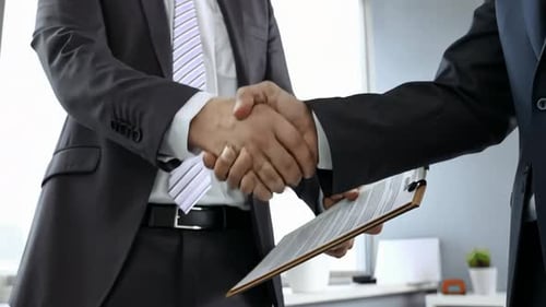 Two Adults in Suits Shaking Hands in Office