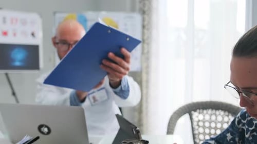 Doctors Discussing Patient Report During Medical Meeting in Clinic