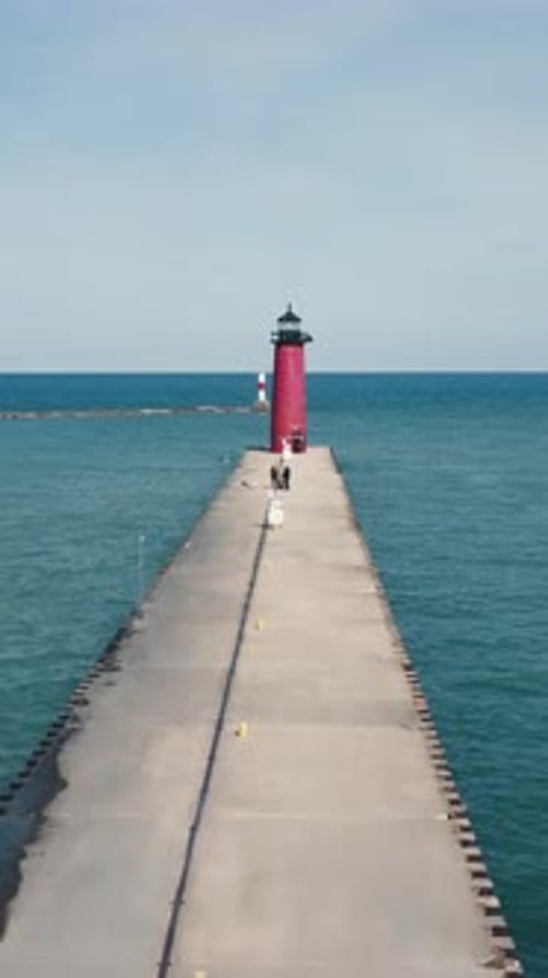 A Red Lighthouse Stands Proudly at the Lake Port During Cloudy Weather Its Reflection Shimmers on