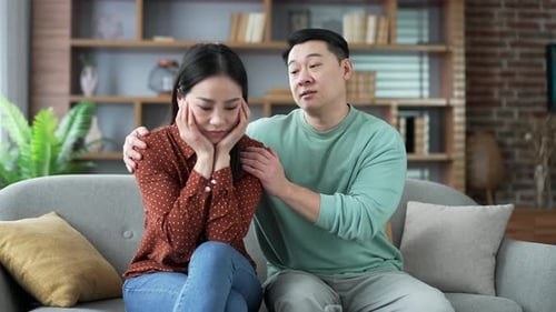 Man Comforts a Sad Woman on Sofa