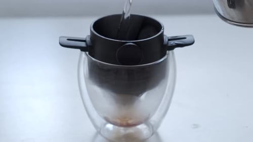 Making Brewed Coffee. Pouring Hot Water Into Double Wall Glass With Ground Coffee In A Filter. close