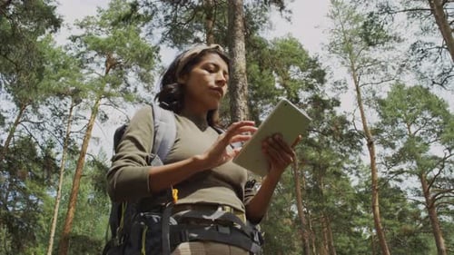 Senderista femenina con mapa digital en busca de direcciones en el bosque