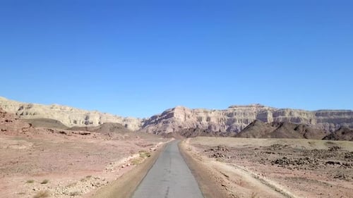 Empty desert road with mountains and blue sky in the background