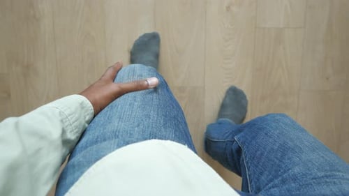 Adult Seated in Denim Jeans on Wooden Floor