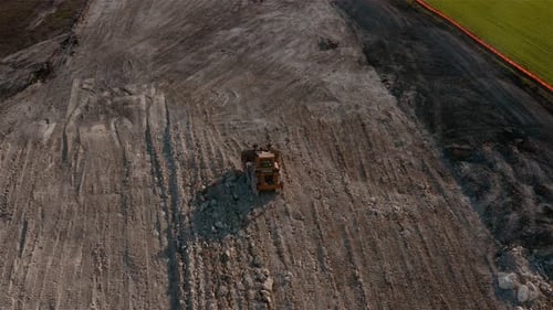 Rear shot of a multi terrain tractor compacting the dirt of a building foundation om a construction