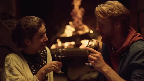 Cozy couple toasting with wine by a fireplace