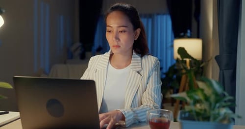 Woman Works On Laptop At Home At Night