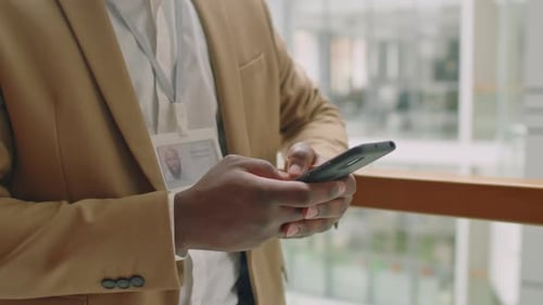 Mann im formellen Anzug, der SMS-Nachrichten in seinem Handy schreibt