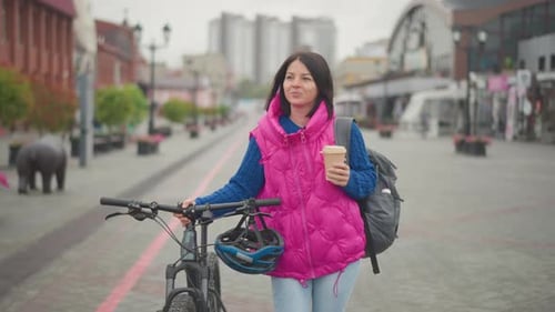 Woman Walking with Bike and Coffee in City
