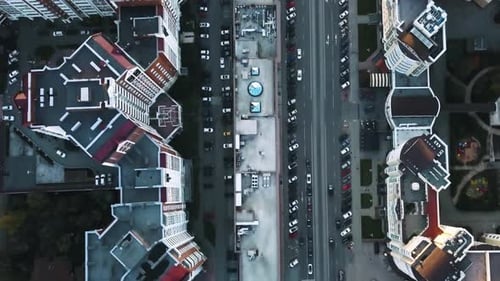 Cars Driving on a Road Between Residential Buildings