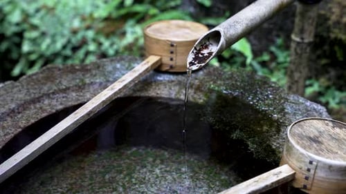 Japanese Water Fountain With Bamboo Ladles Resting On Side. Close Up, Slow Motion Shot