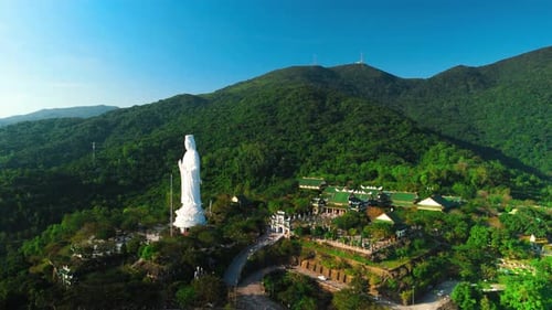 Aerial Panorama Capturing White Lady Buddha Statue Rising Above Verdant Mountainside Overlooking