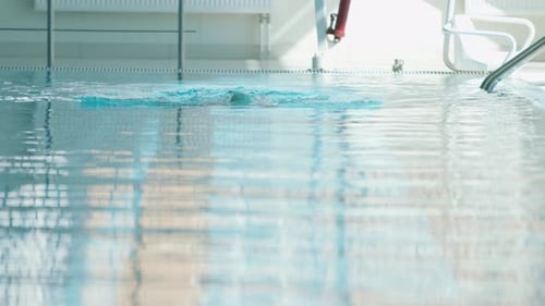 A Young Girl in Turquoise Swimming Cap Training in the Pool and Swims with a Breaststroke