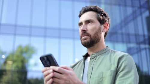 Bearded Man Using Smartphone Outside Office Building