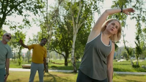 Group Doing Stretching Exercises in Sunny Urban Park