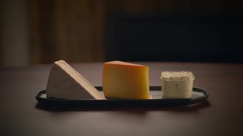 Hand Grabs Cheese From Tray on Wooden Table