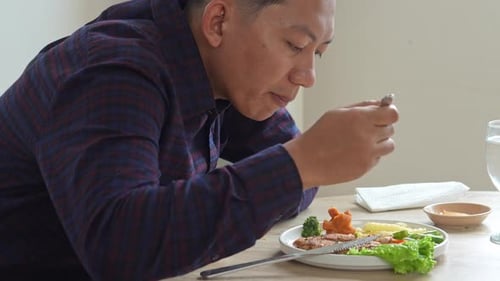 Man Eating Steak and Vegetables at Table