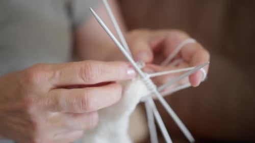Woman Knitting a White Wool Sock Indoors