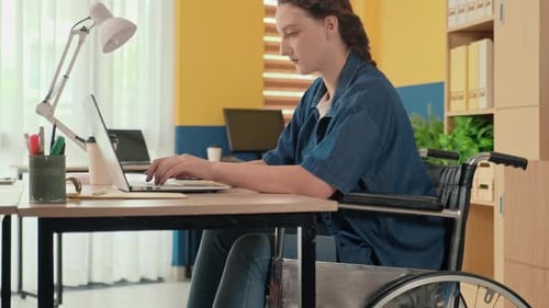 Young Woman in Wheelchair Working on Laptop at Office