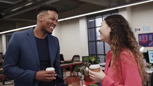 Two happy diverse creative colleagues in discussion in casual office, slow motion