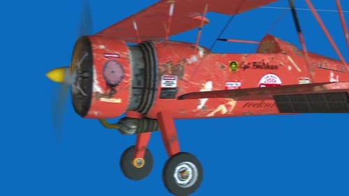 Red biplane flies through clear blue sky