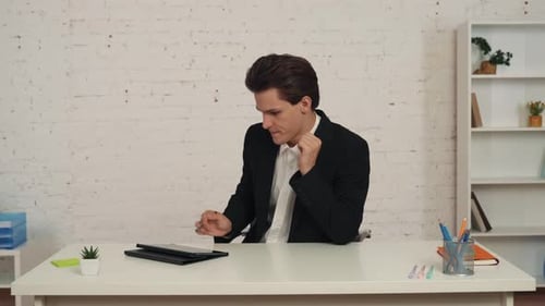 Medium Video of a Young Man Sitting at His Desk in an Office Working at the Tablet and Using Stylus