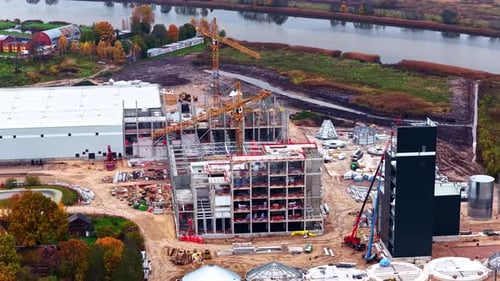 An Industrial Complex is Being Built With Cranes Above a Multi-story Steel Structure - Orbit Drone