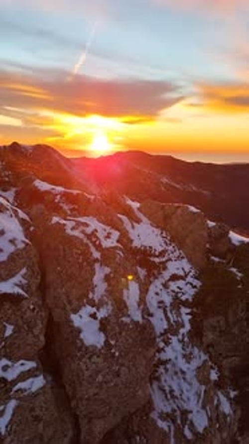 Majestic Aerial View of the Sun Setting Over a Snowy Mountain Range The Golden Hour Light Creates a