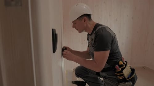Electrician Installing Electrical Outlet in New Home Construction