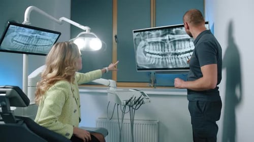 Seitenansicht eines männlichen Zahnarztes, der der Klinik für weibliche Patienten eine MRT-Untersuchung der Zähne zeigt