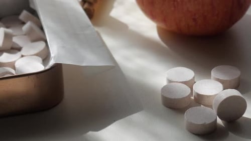 Gros plan sur des bonbons à la menthe ou de la menthe poivrée, une boîte rectangulaire ouverte, des bâtons de cannelle et une pomme rouge.