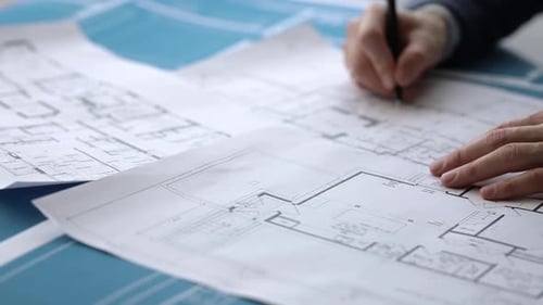 Architekt macht sich Notizen zu Konstruktionszeichnungen