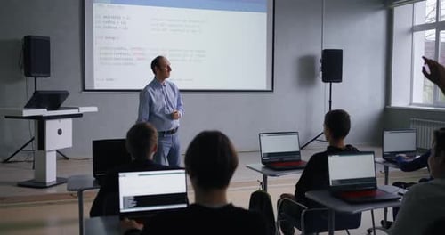 Junge Schüler fragen Lehrerinnen und Lehrer mittleren Alters, Gruppe von Informatik-Schülern