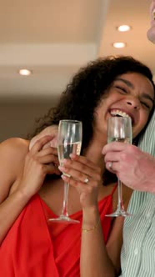 Vertical video: Couple seeing HAPPY 1ST ANNIVERSARY sign in kitchen raising flutes clinking glasses