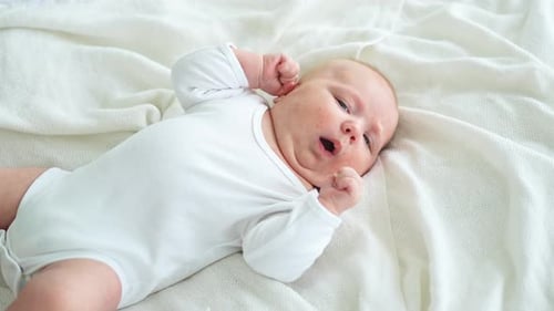 Adorable Baby Relaxing on White Blanket at Home