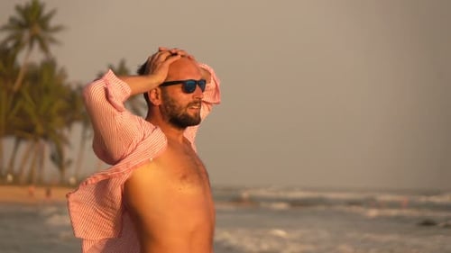 Attractive man stretching arms on tropical beach admiring ocean view in slow motion