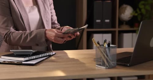 Woman Counting Money at Desk in Home Office