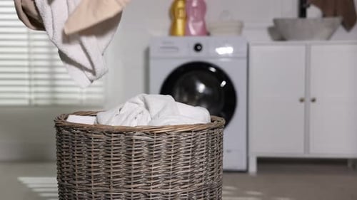 Woman fills laundry basket with towels and clothes