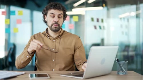 Stressed Man Working at Desk in Modern Office