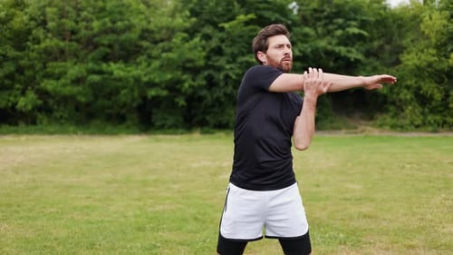 Man Warming Up Stretching Arms in Field