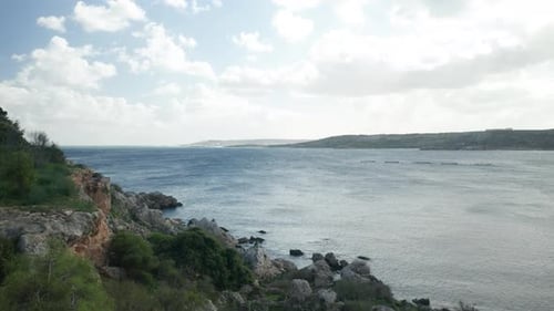 AERIAL: Panoramic Shot of Mellieha Bay on a Sunny Day with Fish Farm Nets Placed in Bay