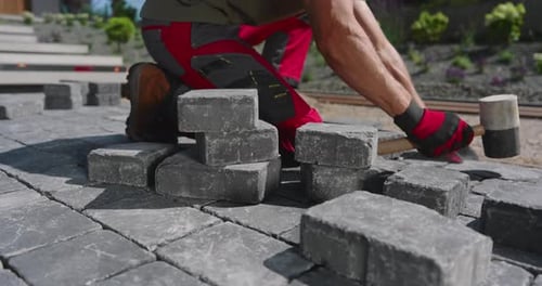 Paving a Pathway With Stone Blocks in a Residential Garden in Bright Sunshine