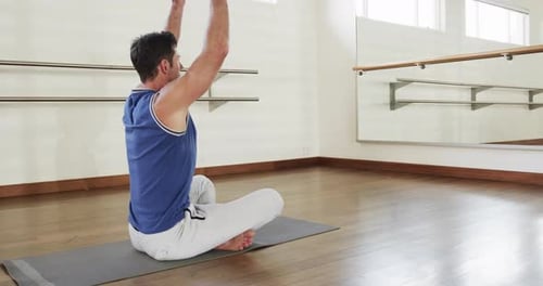 Focused caucasian man practicing yoga meditation in gym, slow motion