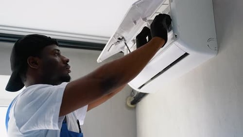 Maintenance Worker Repairing Air Conditioner Inside Home