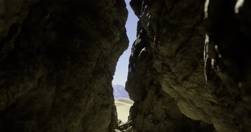 View Through a Narrow Rock Formation Revealing a Desert Landscape at Noon