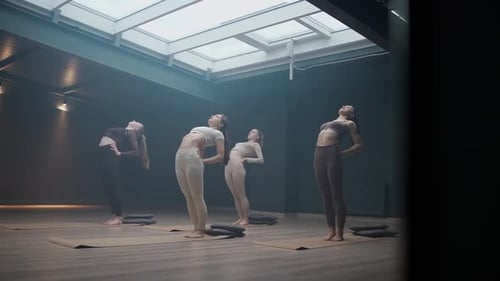 Group of Womens Doing Yoga in a Dark Studio Room Flexible Females Performs a Beautiful Stretching