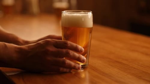 Hands Sliding A Glass Of Beer
