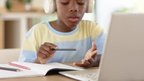 Counting fingertips, African American boy writing homework in notebook with laptop at desk