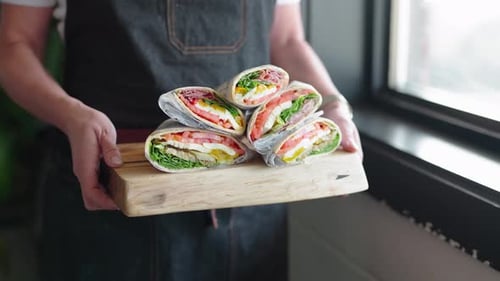 Chef holding a pile of deli sandwiches on a platter. Caterer holds a platter of Italian deli sandwic