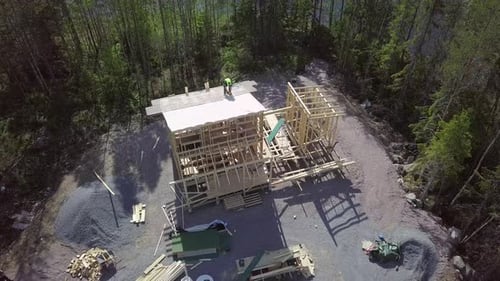 Construction site of a tiny country house with beautiful river shore, builder with nail gun working